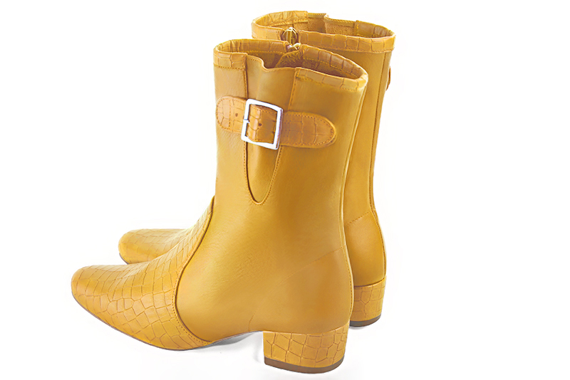 Mustard yellow women's ankle boots with buckles on the sides. Round toe. Low block heels. Rear view - Florence KOOIJMAN